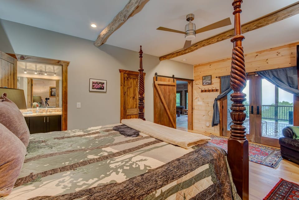 The first level queen bedroom is a true mountain sanctuary — a stunning four-poster bed, private ensuite bathroom, and direct deck access create an elegant and deeply relaxing retreat unlike anything else at Rested Traveler.