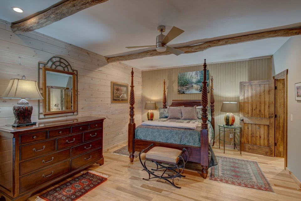 The first level queen bedroom is a stunning rustic retreat — a gorgeous four-poster bed, rich warm wood accents, and a private ensuite bathroom create an elegant and deeply comfortable space guests absolutely love.