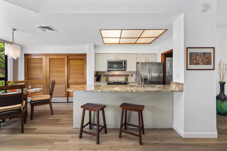 Your open-concept kitchen invites relaxed island dining and easy entertaining, with stainless steel appliances, granite countertops, and warm wood accents throughout.