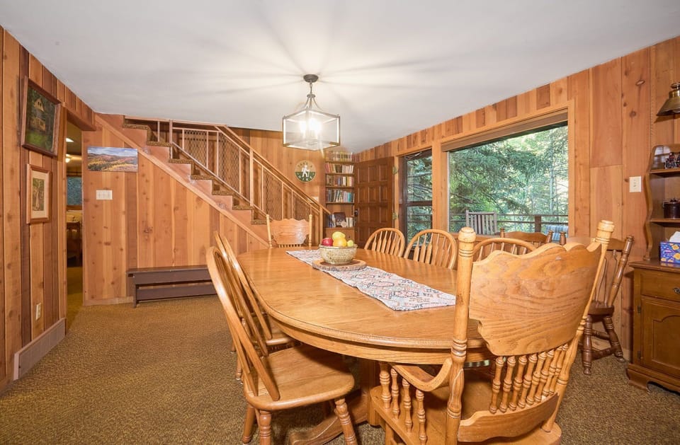 Wide dining room leads into the upper level, wood-paneled walls and natural light throughout