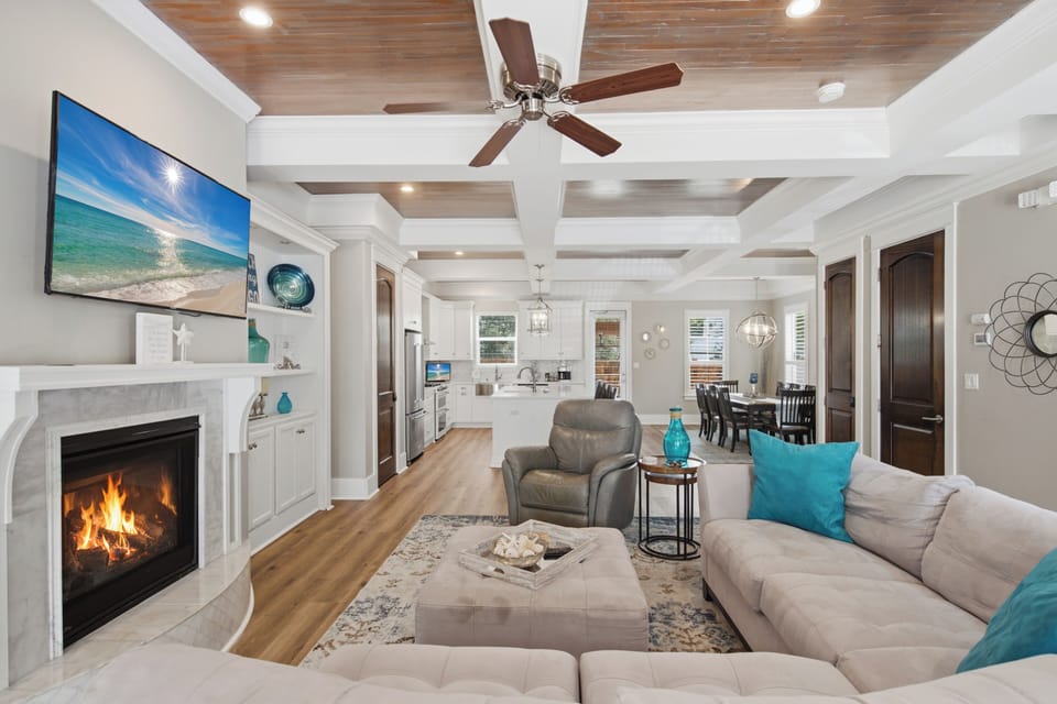 Unwind in your spacious living area, where warm wood tones, a cozy fireplace, and plush seating create a serene coastal escape. Enjoy an open layout connecting to your fully-equipped kitchen and dining space.