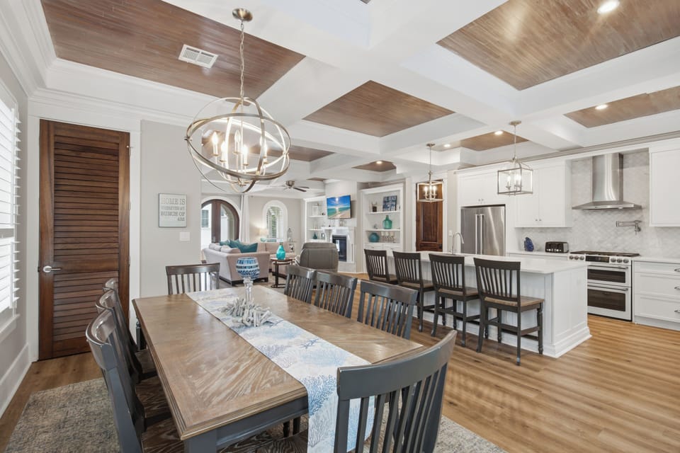 Step into your open-concept living space where warm wood tones and elegant lighting create an inviting atmosphere for gathering, cooking, and making memories together.