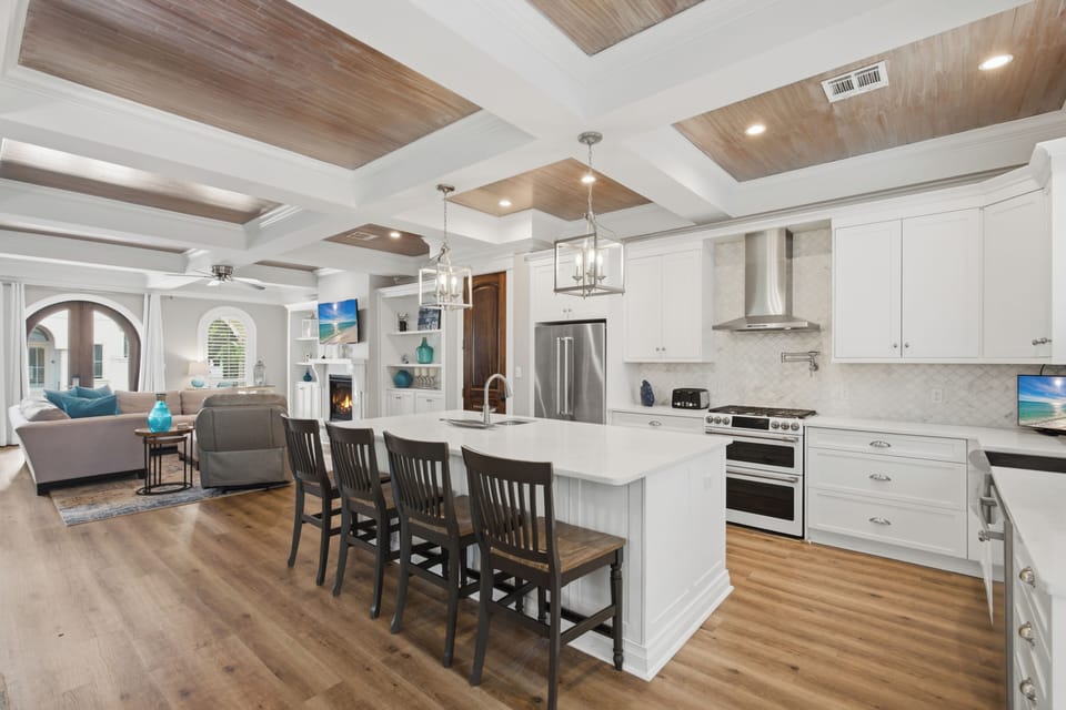 Gather around the spacious island in this bright, open-concept kitchen, where coffered ceilings with warm wood accents invite you to cook, share meals, and make memories together.
