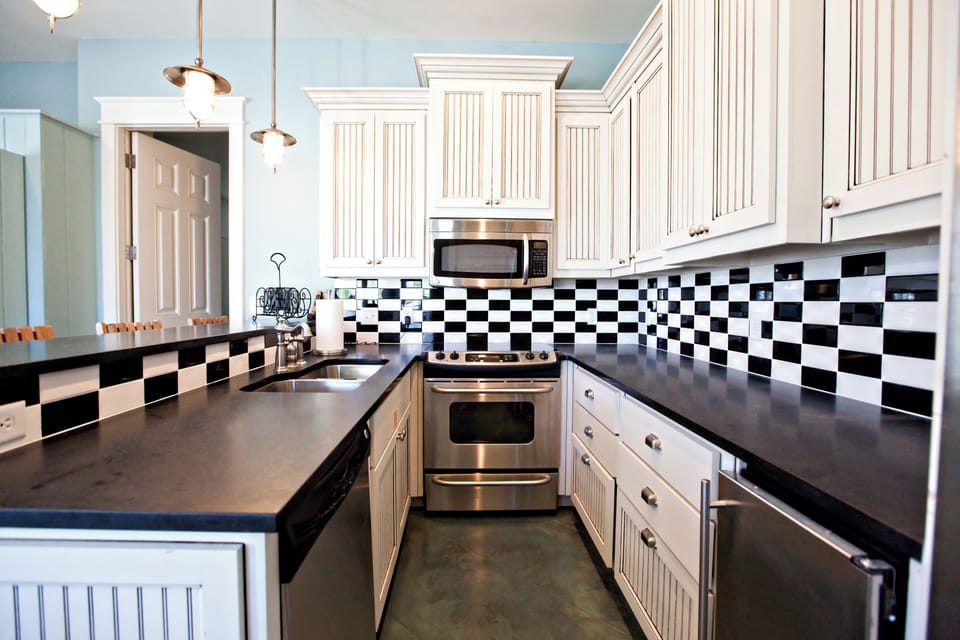 Your fully equipped kitchen features stainless steel appliances, a striking checkered backsplash, and ample counter space to prepare home-cooked meals during your stay.