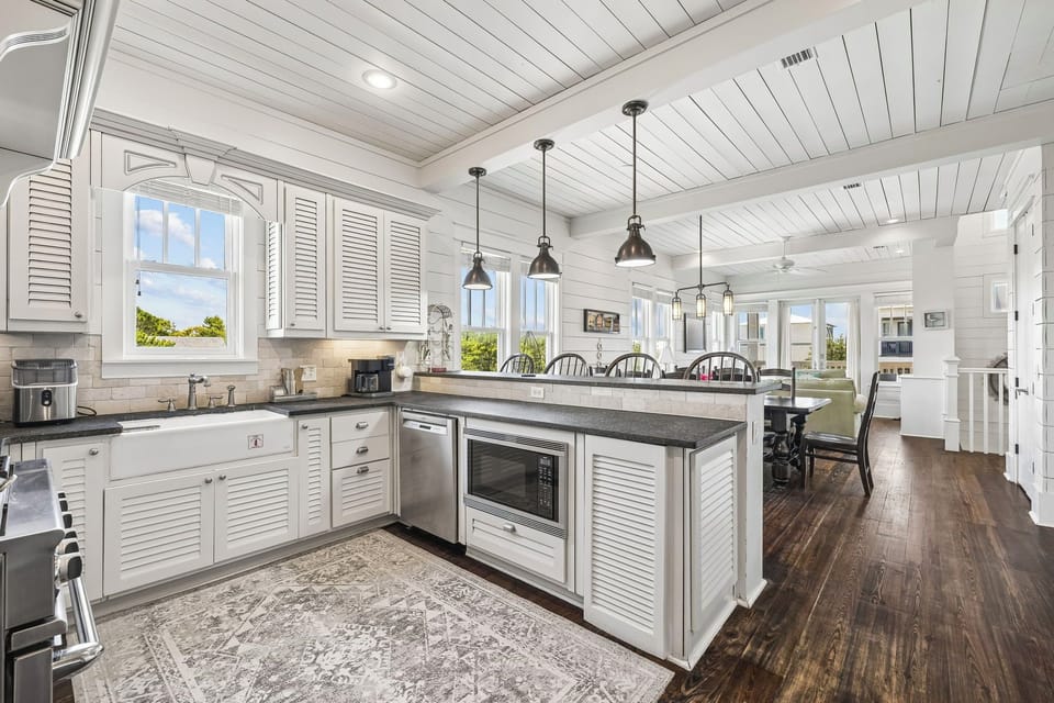 Bright open-concept kitchen featuring stainless steel appliances, gorgeous countertops, and natural light from windows overlooking lush greenery.