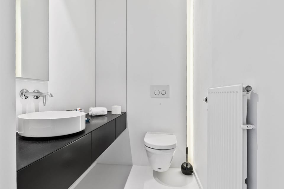 Sleek modern bathroom with vessel basin, illuminated mirror and WC – Grand Ostend townhouse with private sauna, a short walk from Oostende beach