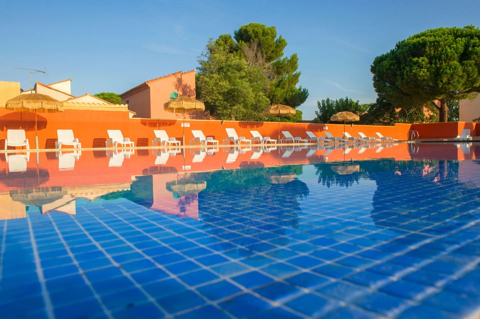 A calm afternoon by the pool, with the domain's low-rise buildings and leafy grounds stretching behind.