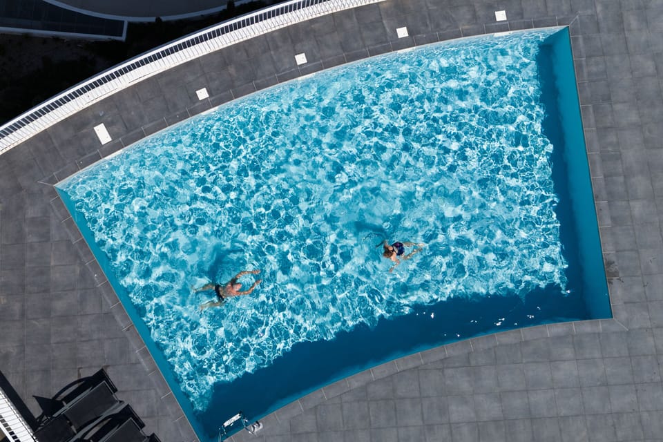 The rooftop heated pool seen from above — open April through October, with turquoise water and a sun-drenched tile deck.