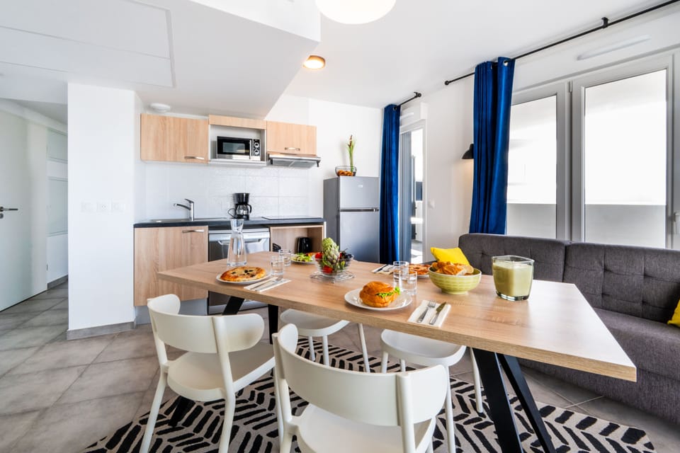 Kitchenette with light wood cabinetry, black countertop, and full appliance set including coffee maker and microwave.