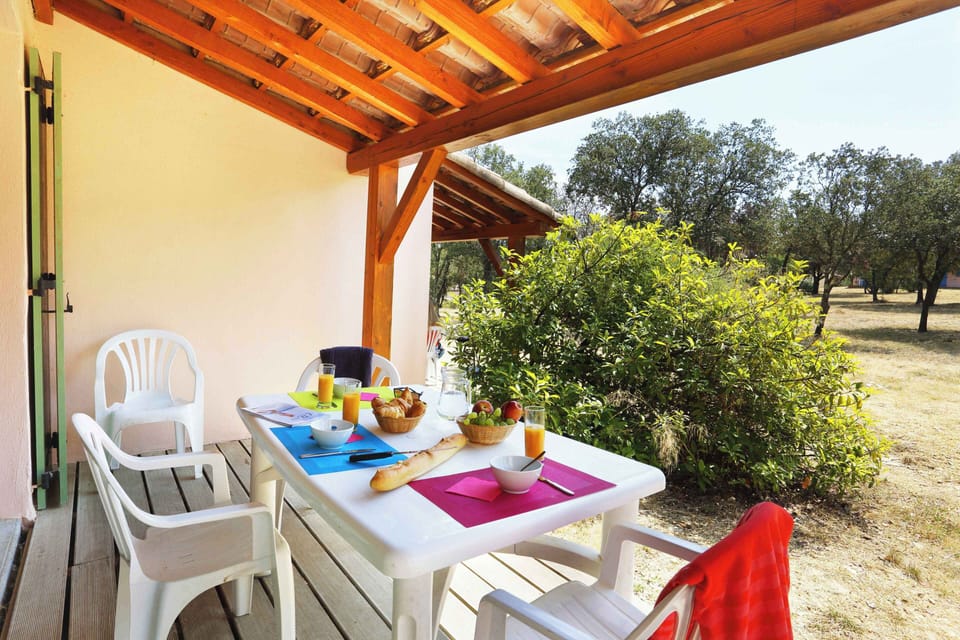 The shaded terrace offers a peaceful outdoor dining spot, surrounded by the Mediterranean trees and garrigue greenery of the estate.