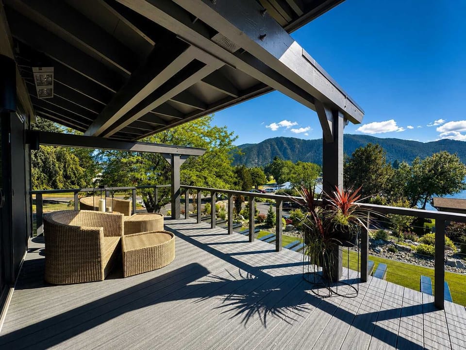 Relax on a sprawling, covered wrap-around deck featuring comfortable wicker lounge seating and panoramic waterfront views.