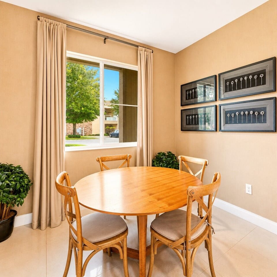 Intimate dining nook with natural wood table, garden views, and framed art