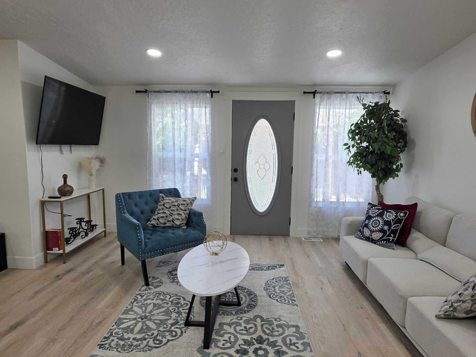 Modern living room with comfortable seating, flat-screen TV, and plenty of natural light. Perfect for relaxing or entertaining.