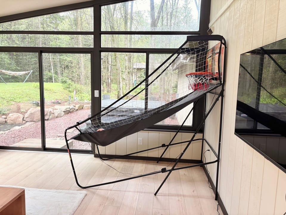 Sunroom fun with arcade basketball, a TV, and the hot tub just steps away