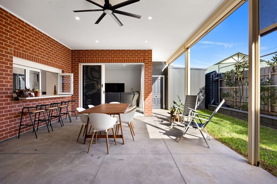 Gather beneath the covered alfresco for long lunches and relaxed evenings, with a six-seater dining table, comfortable outdoor seating, and an easy connection to the backyard lawn.