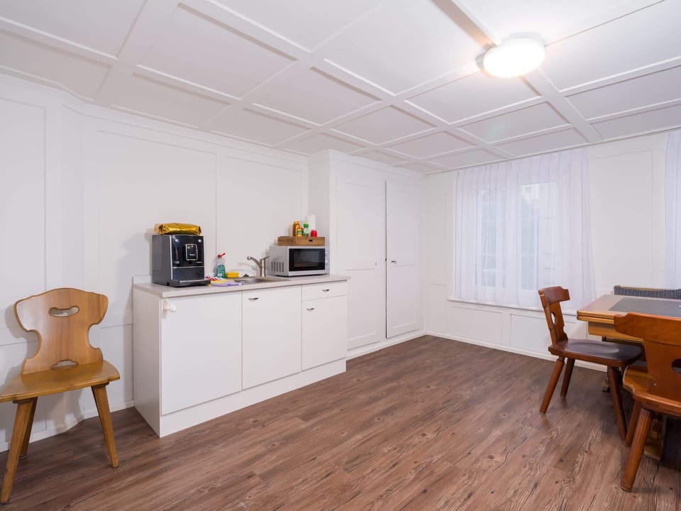 Shared dining area with coffee machine, microwave, small fridge, and seating for simple meals or coffee.