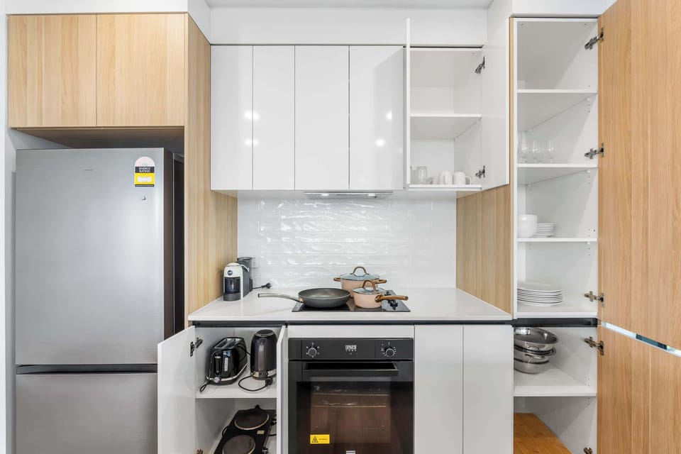 Fully equipped kitchen with oven, cooktop, coffee machine and ample storage.