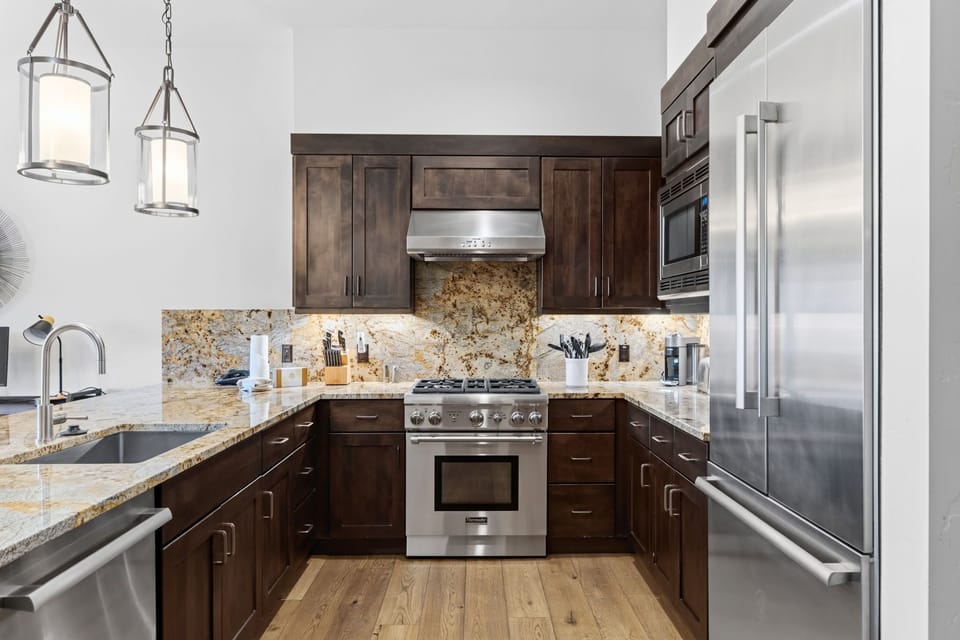 Step into your fully equipped chef's kitchen with gleaming granite counters, stainless steel appliances, and rich wood cabinetry—ready for your culinary adventures.