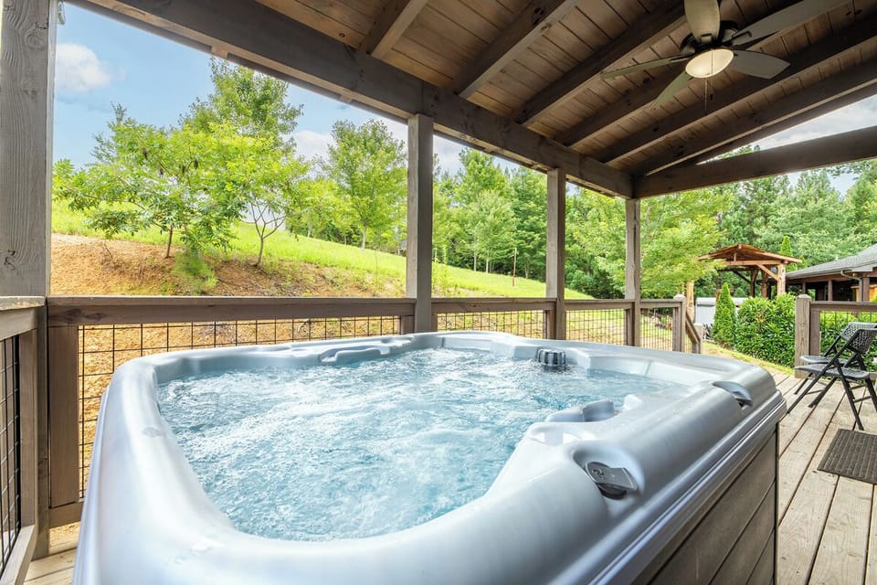 Soak your cares away in this spacious hot tub under a covered porch, surrounded by peaceful hillside greenery and fresh mountain air.