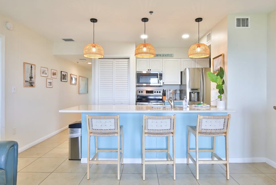  Coastal kitchen with full bar seating — bright, airy, and ready for every meal of the vacation