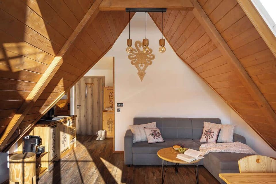Przestronny salon wyposażony jest w wygodną, rozkładaną sofę, idealną do wypoczynku po dniu spędzonym na górskich szlakach lub stokach narciarskich. Z salonu oraz przez duże przeszklenia można podziwiać piękny widok na Tatry.