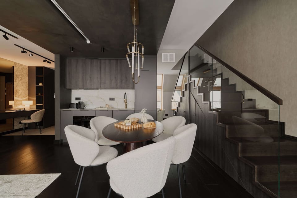 Na pierwszym poziomie znajduje się przestronny salon z rozkładaną sofą, który stanowi wygodną strefę relaksu. Dodatkowym atutem tej części apartamentu jest rzutnik umieszczony nad sofą oraz ekran wysuwany z sufitu.