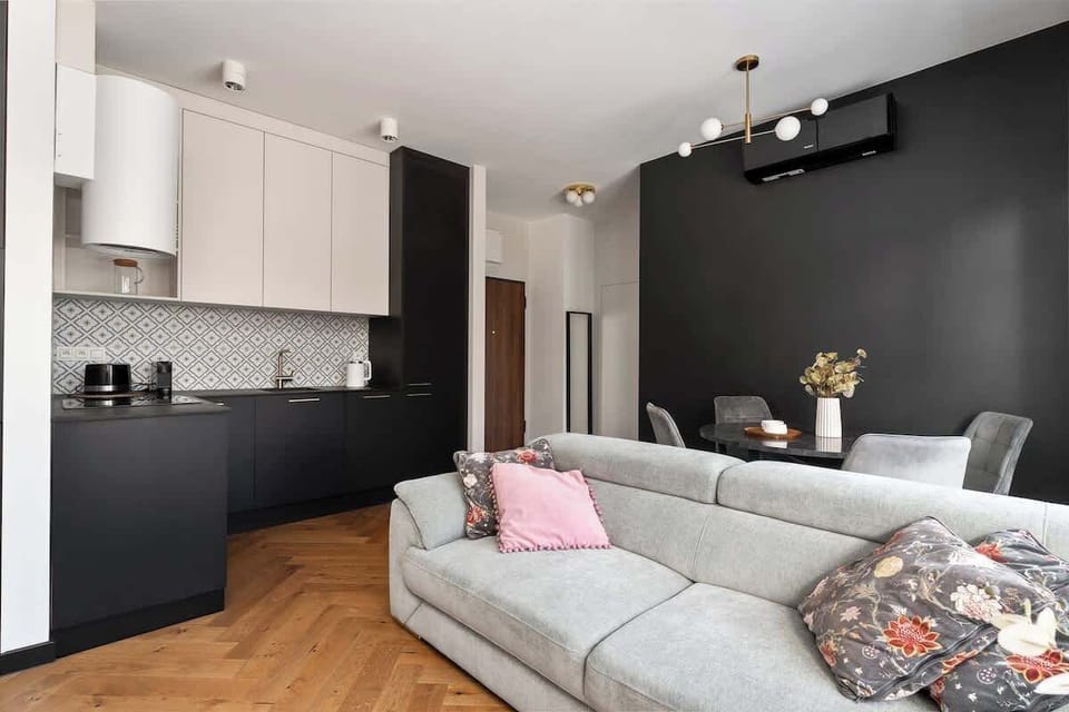 Salon stanowi serce apartamentu i został wyposażony w wygodną, nierozkładaną sofę, która zapewnia komfortowy wypoczynek w ciągu dnia. Naprzeciwko znajduje się telewizor z funkcją Smart TV, idealny na wieczorny relaks.