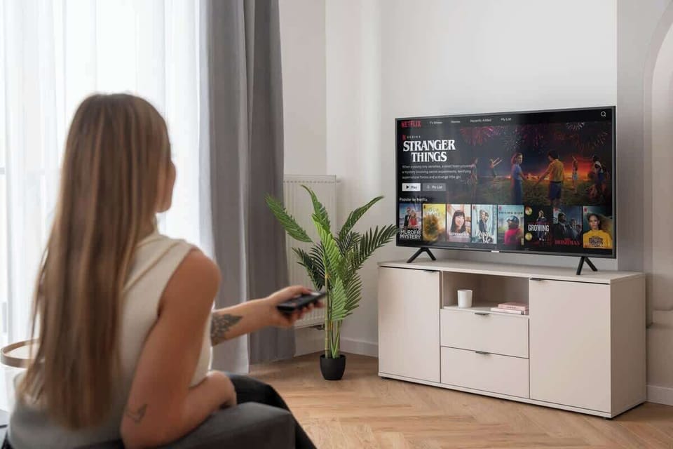 Salon wyposażono w wygodną, rozkładaną sofę, utrzymaną w stonowanych, nowoczesnych odcieniach szarości. Naprzeciwko znajduje się duży telewizor Smart TV z dostępem do kanałów telewizyjnych.