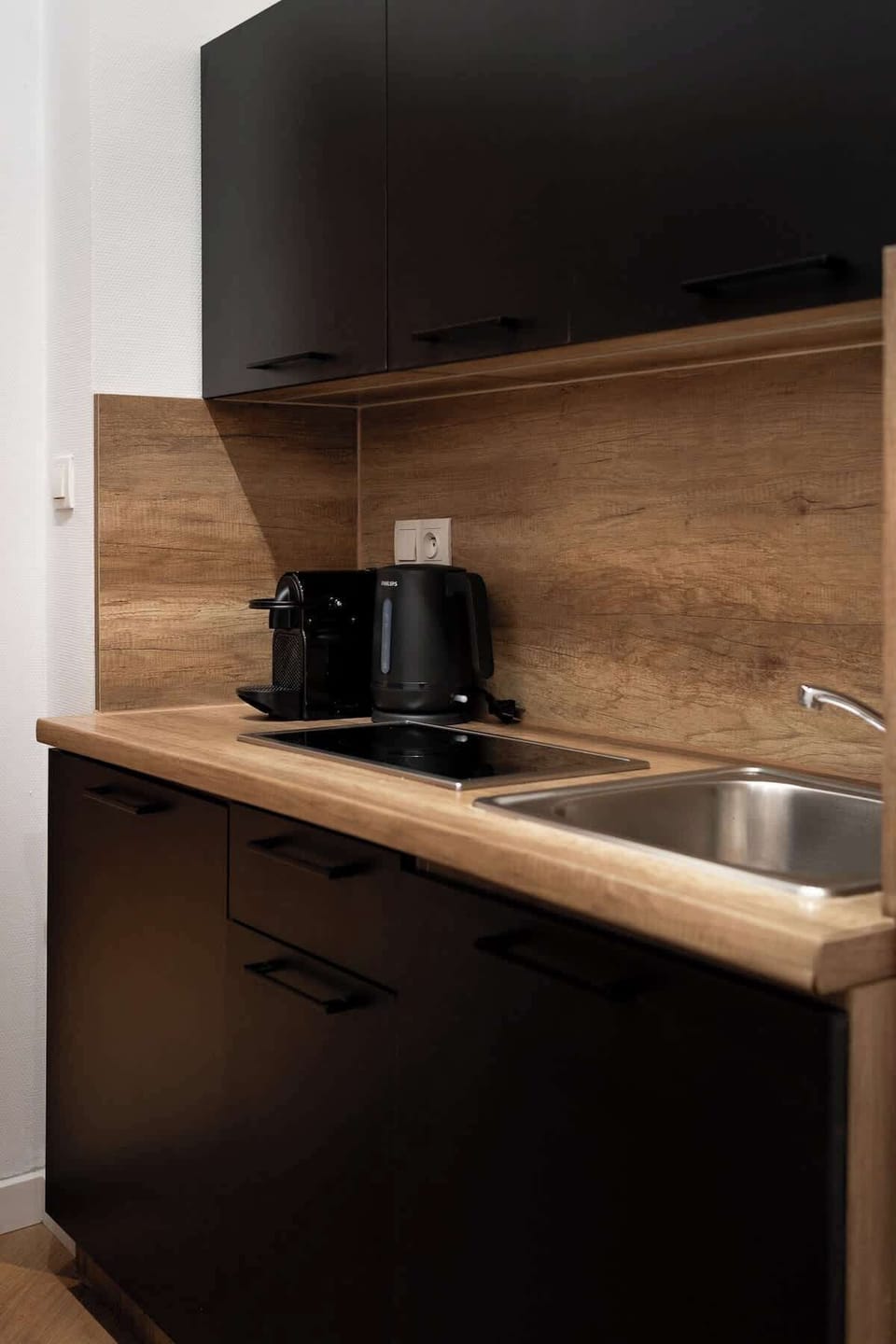 W apartamencie znajduje się również funkcjonalny aneks kuchenny, wyposażony w płytę kuchenną, czajnik elektryczny oraz ekspres do kawy, co pozwala na przygotowanie posiłków i porannej kawy we własnym zakresie.