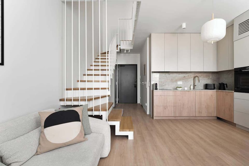 Jasny i nowocześnie urządzony salon stanowi serce apartamentu. Znajduje się tu wygodna, rozkładana sofa oraz stolik kawowy, tworzące przyjemną strefę wypoczynkową. Naprzeciwko umieszczono telewizor z kanałami kablowymi i funkcją Smart TV.