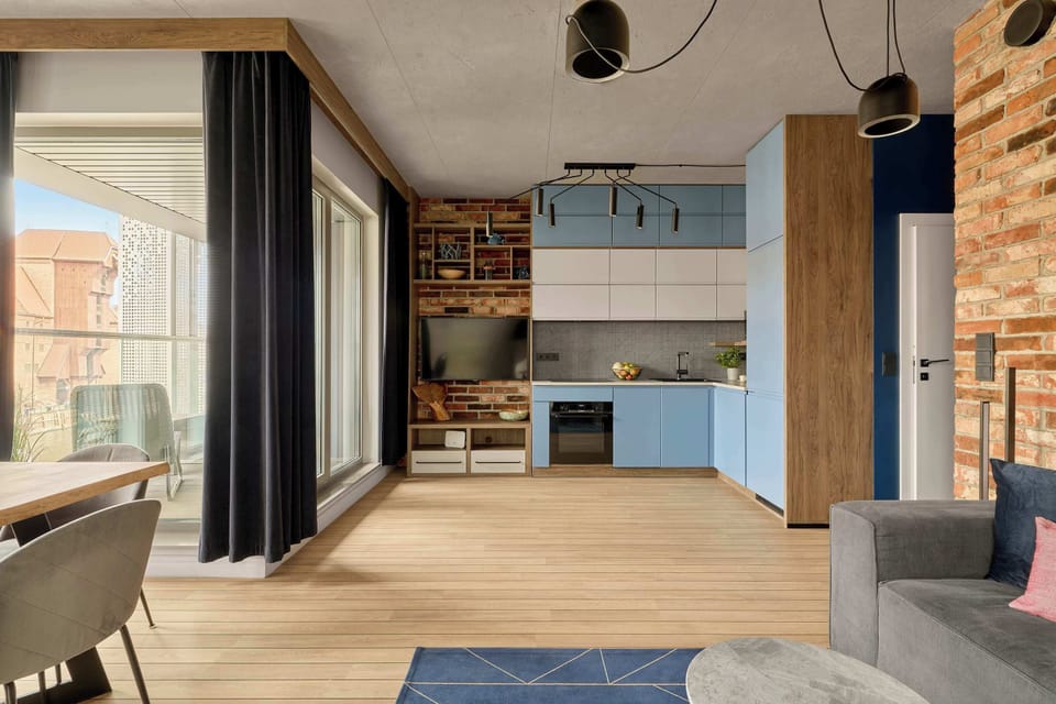 Centralną częścią apartamentu jest salon połączony z aneksem kuchennym. W salonie znajduje się rozkładana sofa z funkcją spania oraz telewizor z dostępem do kanałów kablowych i funkcji Smart TV.
