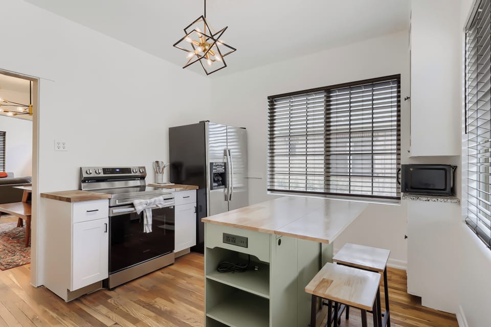 You'll love preparing meals in this bright, modern kitchen with its stylish island seating, stainless steel appliances, and warm wood countertops that invite your culinary creativity.
