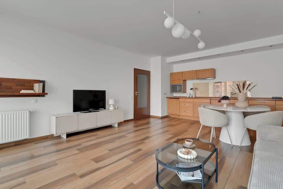 Największym atutem salonu są panoramiczne okna z widokiem na rzekę Motławę i zabytkową zabudowę Starego Miasta. Wygodna, rozkładana sofa z funkcją spania, duży telewizor i elegancki stół jadalniany sprzyjają wspólnemu spędzaniu czasu.