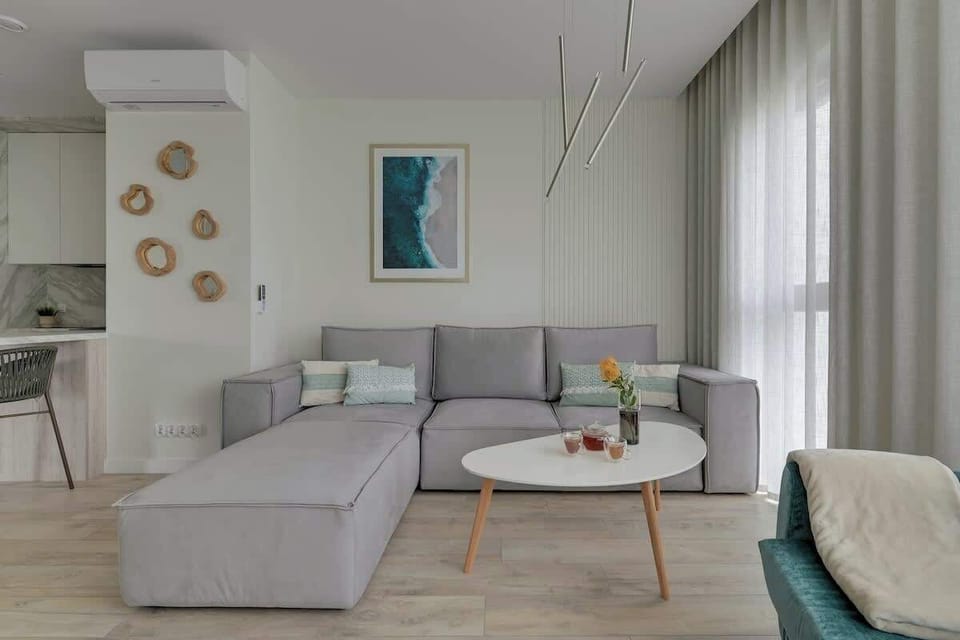 Przestronny, klimatyzowany salon wyposażony jest w rozkładaną sofę, elegancki fotel i stolik kawowy. Naprzeciwko znajduje się telewizor z i funkcją Smart TV, umożliwiający dostęp do ulubionych serwisów streamingowych.