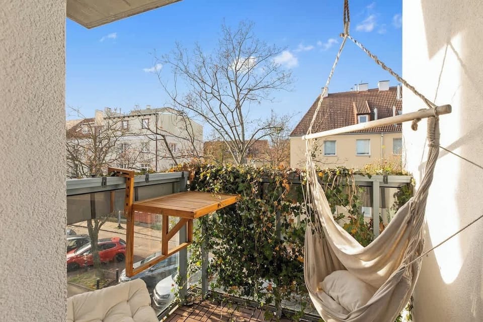 Z pokoju dziennego można wyjść na balkon, idealny na poranną kawę lub wieczorny odpoczynek. Na gości czeka tam wygodna huśtawka w formie wiszącego fotela, tworząca przytulne miejsce do relaksu na świeżym powietrzu.
