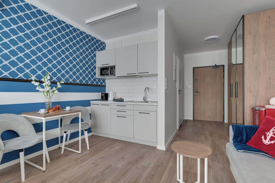 Apartament wyposażony jest w funkcjonalny aneks kuchenny, który umożliwia wygodne przygotowywanie posiłków. Do dyspozycji gości są płyta indukcyjna, mikrofala, lodówka, zmywarka, pralka, ekspres do kawy oraz czajnik. 