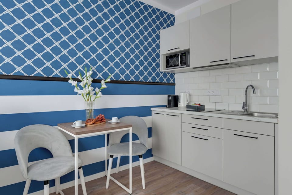 Apartament wyposażony jest w funkcjonalny aneks kuchenny, który umożliwia wygodne przygotowywanie posiłków. Do dyspozycji gości są płyta indukcyjna, mikrofala, lodówka, zmywarka, pralka, ekspres do kawy oraz czajnik. 