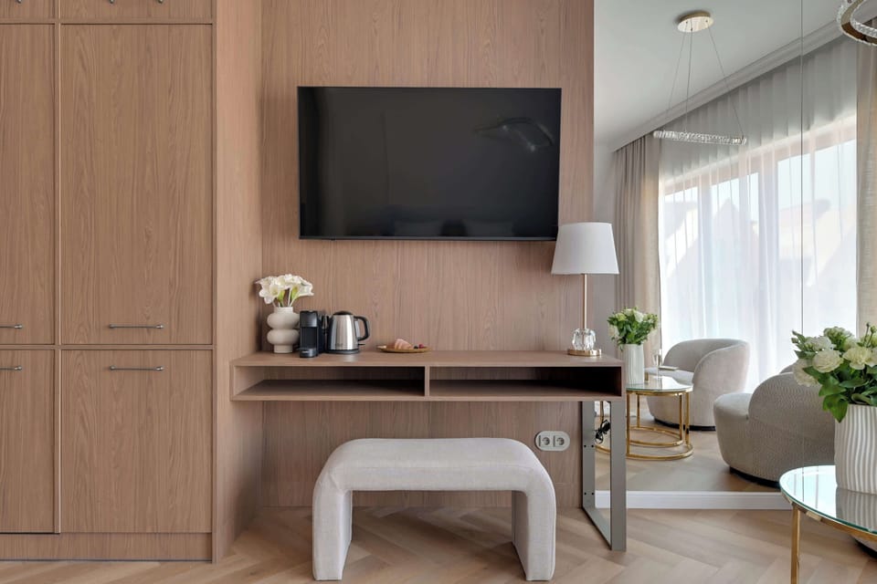 Elegancka część wypoczynkowa z telewizorem, wygodnymi fotelami i dużą zabudową zapewniającą mnóstwo miejsca do przechowywania. Jasne wnętrze, designerskie dodatki i stonowana kolorystyka tworzą atmosferę komfortu i relaksu.