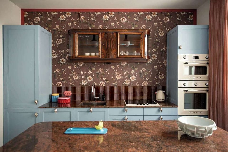 The separate kitchen combines functionality with unique design. Blue fronts, wooden elements, decorative wallpaper, and stylish details create an impressive interior. It is fully equipped with an induction cooktop, dishwasher, and microwave oven, wit