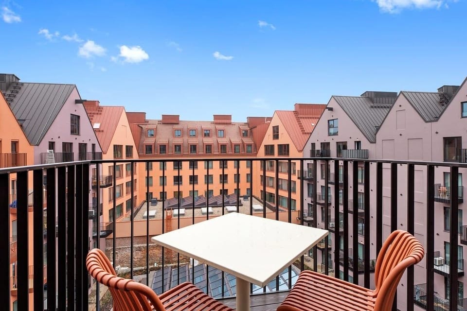 Prywatny balkon z dwoma wygodnymi krzesłami i stolikiem pozwala cieszyć się poranną kawą lub chwilą wytchnienia na świeżym powietrzu. Widok na spokojny, zielony dziedziniec tworzy idealne tło do odpoczynku.