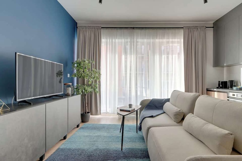 Przytulny salon oferuje wygodną, rozkładaną sofę ustawioną naprzeciw telewizora z kanałami oraz funkcją Smart TV, co zapewnia idealne warunki do relaksu po aktywnym dniu.