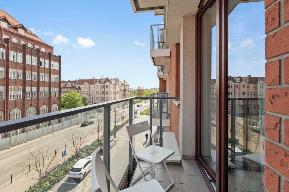 Balkon z miejscem do siedzenia oferuje widok na spokojną okolicę i zabudowę miasta. To idealna przestrzeń na poranną kawę lub chwilę relaksu na świeżym powietrzu.