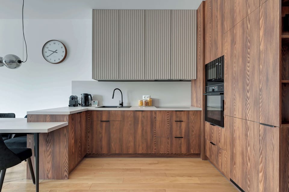 Elegancka kuchnia w nowoczesnym stylu zachwyca połączeniem naturalnego drewna, minimalistycznych form i wysokiej jakości wykończenia. W pełni wyposażona przestrzeń zapewnia komfort zarówno podczas krótkiego, jak i dłuższego pobytu.