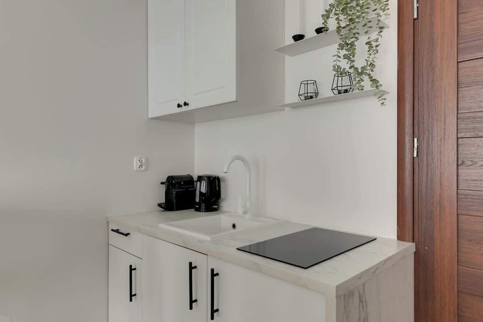 Apartament posiada aneks kuchenny z płytą, czajnikiem i ekspresem do kawy, stół jadalniany z funkcją miejsca do pracy oraz zestaw powitalny z kawą, herbatą i podstawowymi przyprawami.