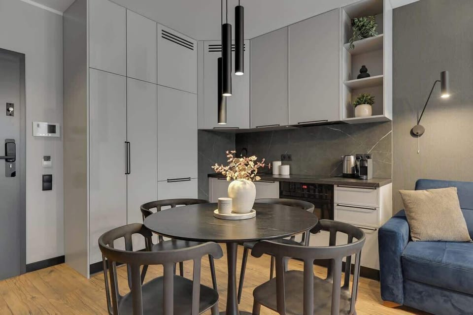 Nowoczesna, w pełni wyposażona kuchnia z elegancką strefą jadalnianą, utrzymana w minimalistycznym stylu. Funkcjonalny układ, designerskie oświetlenie i wysokiej jakości wykończenie zapewniają komfort podczas codziennego użytkowania.