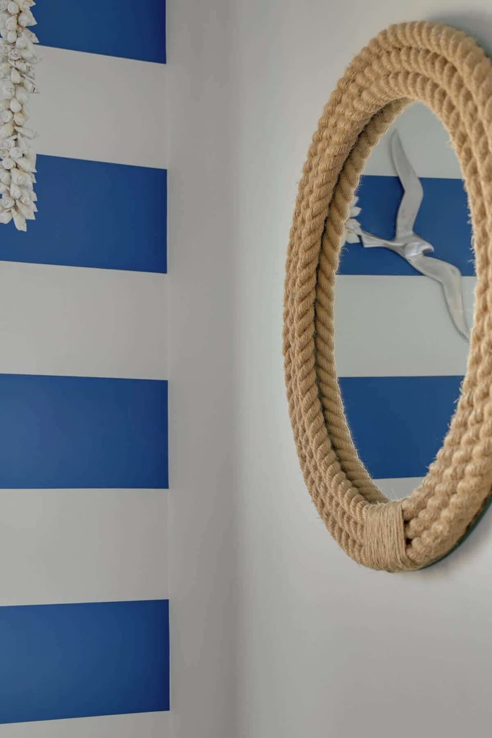 Sypialnia oferuje wygodne łóżko małżeńskie i pojemną szafę. Delikatne motywy marynistyczne – tapeta z żaglówkami oraz biało-granatowe akcenty – nadają wnętrzu nadmorski charakter.