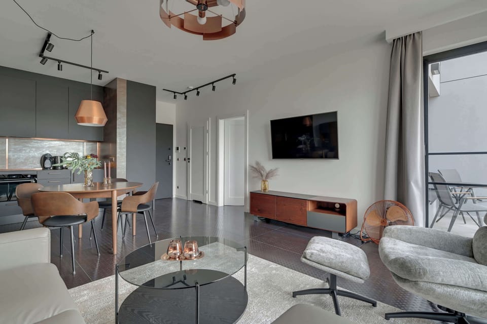 Znajduje się tu rozkładana sofa, która zapewnia wygodne miejsce do relaksu w ciągu dnia i dodatkową przestrzeń do spania. Obok ustawiono komfortowy fotel z podnóżkiem, tworzący idealny kącik do odpoczynku z książką lub kawą.
