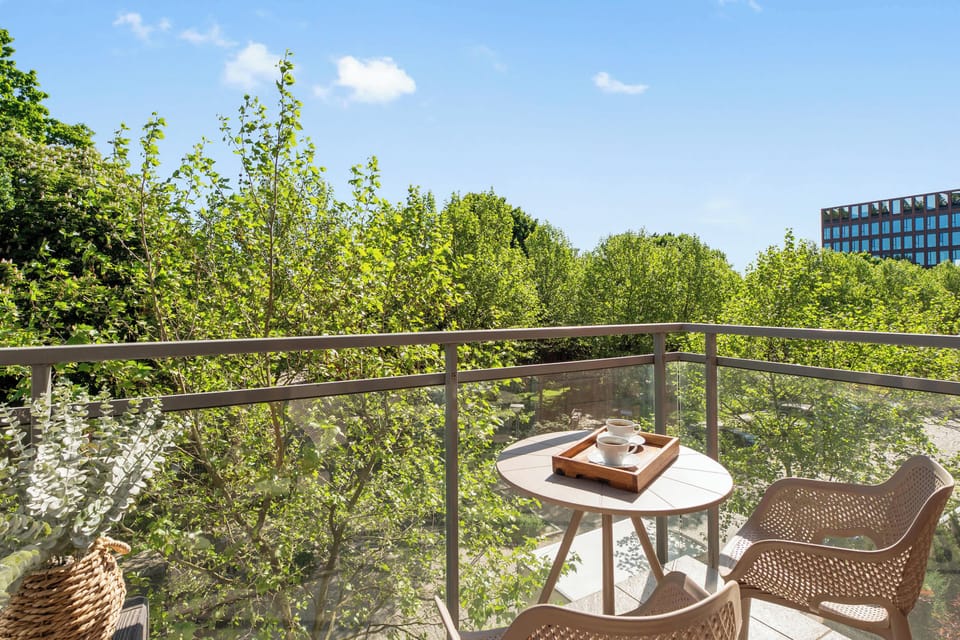 Prywatny balkon z widokiem na zieleń to idealne miejsce na poranną kawę lub wieczorny relaks. Wyposażony w stolik i wygodne krzesła, pozwala cieszyć się spokojną atmosferą oraz świeżym powietrzem.