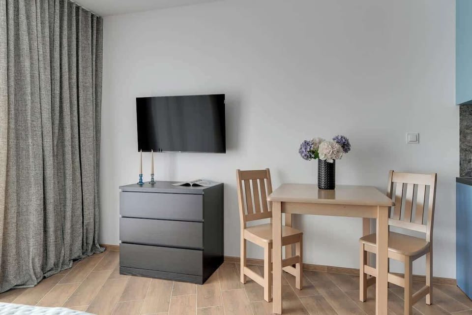 Nowoczesne studio wyposażone w komfortowe łóżko małżeńskie, naprzeciw którego znajduje się telewizor z kanałami kablowymi i funkcją SMART TV. To idealne miejsce do wypoczynku po dniu spędzonym w mieście.