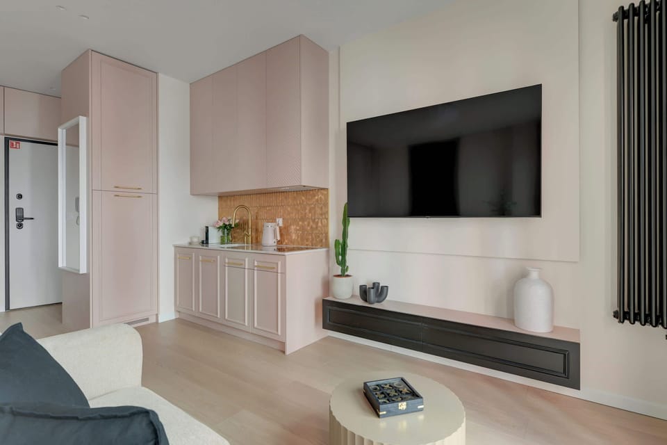 Główną część apartamentu stanowi otwarta przestrzeń łącząca salon i sypialnię. Znajduje się tu wygodne łóżko małżeńskie, sofa oraz telewizor z funkcją Smart TV.